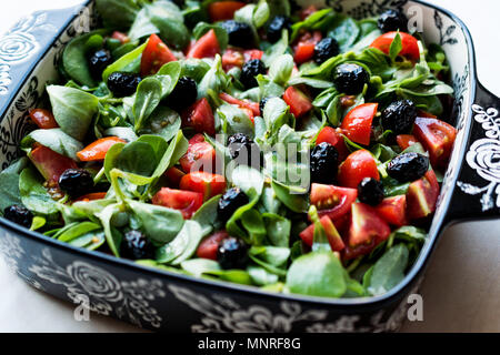 Le pourpier salade avec tomates et olives noires en Bol en porcelaine. L'alimentation biologique. Banque D'Images