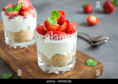 Gâteau au fromage aux fraises dans les verres avec des fraises fraîches et fromage à la crème sur fond de bois. Maison saine potrion dessert. Banque D'Images