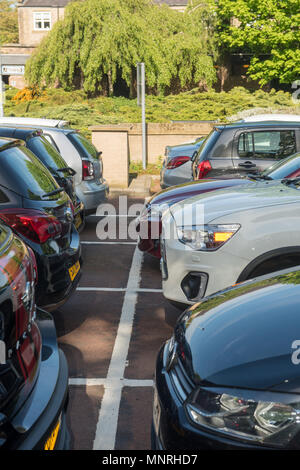 Voitures garées étroitement ensemble dans un parking urbain complet par une journée ensoleillée au Royaume-Uni, montrant des espaces étroits, des véhicules modernes et des facili de stationnement bien utilisés Banque D'Images