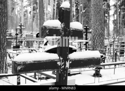 Image en noir et blanc d'une vieille croix de bois recouvert de neige sur la tombe d'un cimetière orthodoxe dans l'hiver Banque D'Images