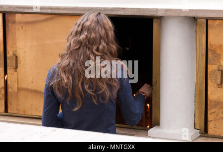 Femme cierge d'éclairage offrant aka et sacrificiel ou memorial bougies allumées dans une église. Banque D'Images