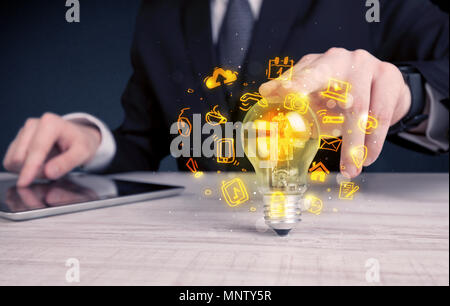 Un bureau commercial promouvoir ses idées de concept avec l'illustration des médias en ligne et les logos de l'appareil autour de l'ampoule en verre électrique. Banque D'Images