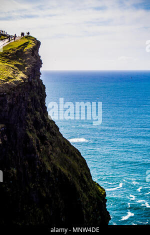 Les touristes en haut des falaises de Moher, un jour ensoleillé, dans le comté de Clare, Irlande Banque D'Images