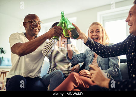 Rire de groupe divers young businesspeople toasting ensemble tout en célébrant avec beers in a modern office Banque D'Images