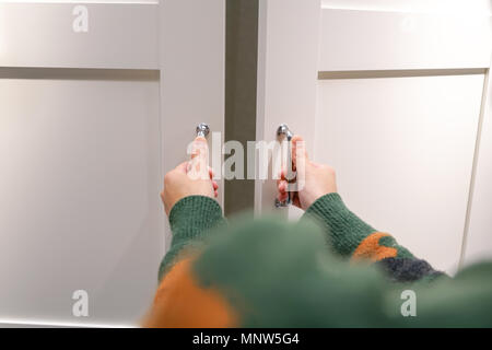 Les mains des femmes ouvre le placard/porte de placard, porte en bois blanc Banque D'Images