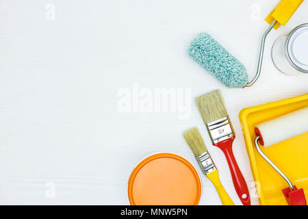 Cans de peinture orange et blanche, pinceaux, rouleaux, peinture sur piste plate en bois blanc voir Banque D'Images