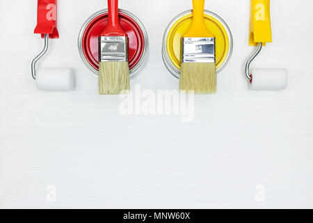 Boîtes de peinture et un ensemble de rouleaux à peinture et pinceaux sur fond d'un bureau en bois. Vue de dessus Banque D'Images