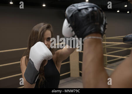 L'homme est la formation d'une jeune fille boxer dans le ring. Banque D'Images