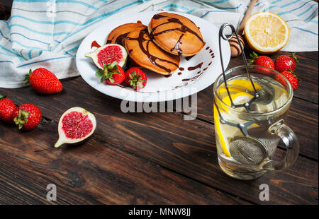 Tasse de thé et des pancakes aux figues, fraises sur plaque blanche libre. Banque D'Images