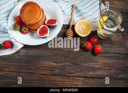 Tasse de thé et des pancakes aux figues, fraises sur plaque blanche libre. Banque D'Images