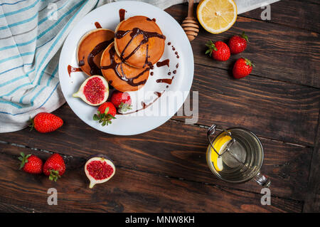 Une tasse de thé et des pancakes aux figues, fraises sur plaque blanche libre. Banque D'Images