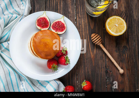 Tasse de thé et des pancakes aux figues, fraises sur plaque blanche libre. Banque D'Images