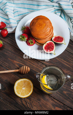 Tasse de thé et des pancakes aux figues, fraises sur plaque blanche libre. Banque D'Images