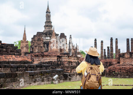 Tourisme asiatique femme prendre une photo de l'ancien temple de la Pagode de l'architecture thaï au parc historique de Sukhothai, Thaïlande. Female traveler in casual thai c Banque D'Images