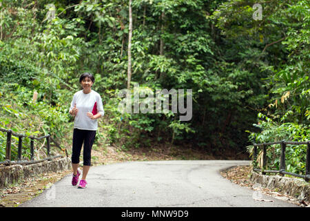 Vue avant du senior woman jogging through park Banque D'Images