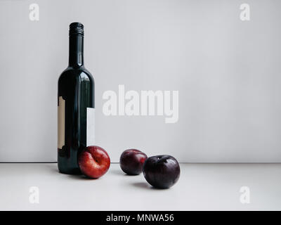 Les prunes mûres fraîches Bouteille de vin rouge avec les prunes mûres sont sur fond blanc Photo modèle avec copie espace pour bannières et affiches Banque D'Images