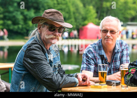 Personnes âgées, un homme avec une moustache colorés, portant des lunettes et un chapeau, boire de la bière avec des amis à un festival d'aliments de rue dans la ville de Hale (Vente Banque D'Images