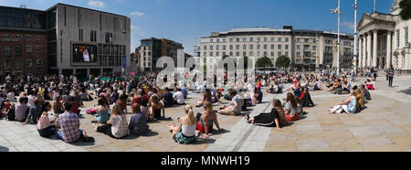 Leeds, West Yorkshire, Royaume-Uni 19 Mai, 2018. Le mariage royal à Leeds, West Yorkshire. Les foules se sont réunis pour regarder le mariage du prince Harry et Meghan Markle sur le grand écran dans Leeds Millennium Square à soleil la foule applaudi pour le Prince et Meghan mais peut le plus fort cheer a été pour la reine quand elle est apparue sur l'écran. Photo panoramique. Credit : James Gibson R/Alamy Live News. Banque D'Images