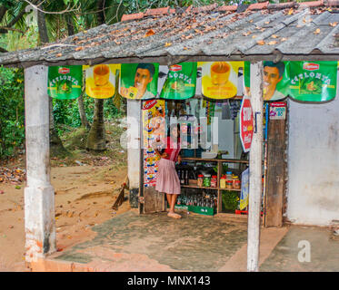 Village girl debout à l'extérieur d'un magasin local de Negombo, Sri Lanka Banque D'Images