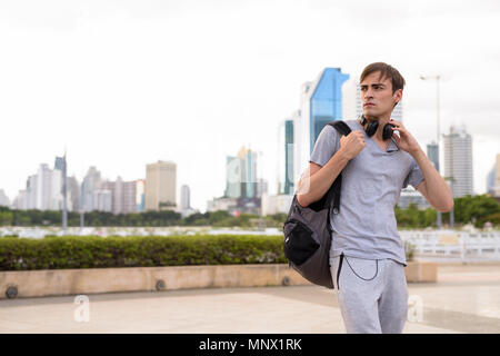 Beau jeune homme portant un casque tout en vous relaxant dans le parc Banque D'Images