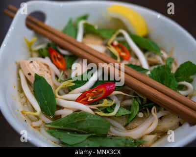 Belle et appétissante photo d'une soupe poulet et nouilles traditionnelles vietnamiennes, également appelé pho ga dans un bol blanc avec fond de bois et luxuri Banque D'Images