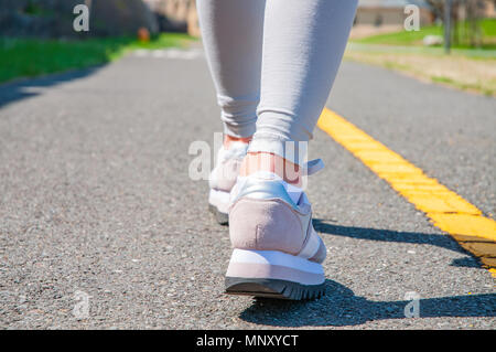 La marche à pied. Close-up of women's chaussures de course sur un chemin pavé. Les pieds de sneakers. Banque D'Images