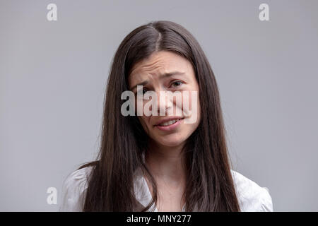 Portrait de jeune femme aux cheveux long avec grimace sur son visage Banque D'Images