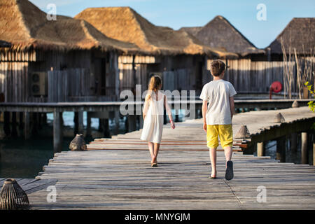 Les jeunes frère et sœur marche sur la passerelle en bois pendant les vacances d'été à luxury resort Banque D'Images