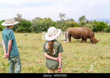 Vue arrière d'enfants sur safari à pied près de white rhino Banque D'Images