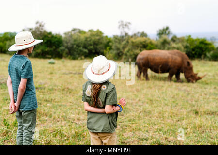 Vue arrière d'enfants sur safari à pied près de white rhino Banque D'Images