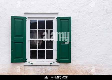 Vieille fenêtre avec des volets verts sur un mur blanc Banque D'Images