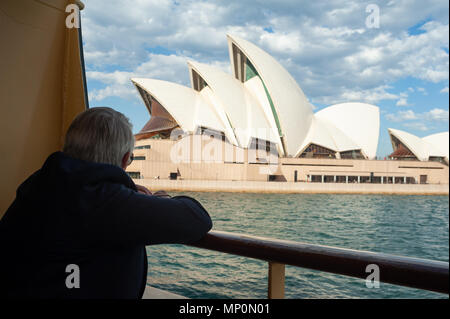 10.05.2018, Sydney, Nouvelle-Galles du Sud, Australie - un homme à bord du Ferry Manly se penche sur l'impressionnante ville de Sydney avec l'Opéra de Sydney. Banque D'Images