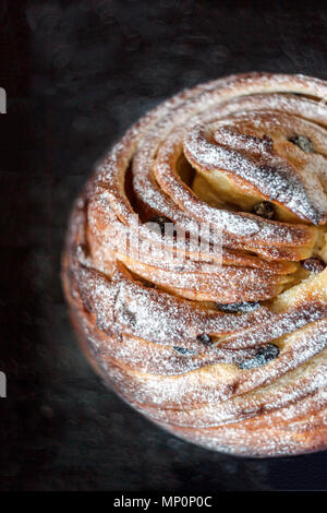 Gâteau Cupcake crunch sous la forme d'un rouleau saupoudré de sucre en poudre sur un fond sombre et un ancien auvent. Pâques et Noël cuisson. Haut de page vi Banque D'Images