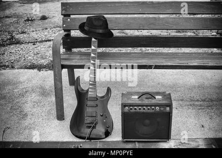 Vieille guitare et l'amplificateur à côté d'un banc de parc, un concept de la musique de rue Banque D'Images