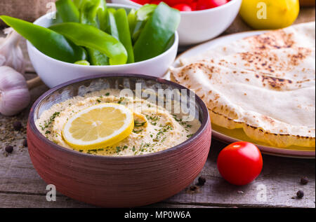 Dans l'hummus accueil Bol en céramique conçue, poivron vert, chapati sur fond de bois naturel. Banque D'Images