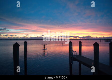 Superbe coucher de soleil colorés avec des nuages sur la côte du golfe de Floride. Homme debout sur paddle board, découpé le long des quais. Banque D'Images