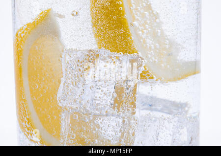 Tranches de citron jaune juteux frais avec de la glace dans l'eau. Banque D'Images