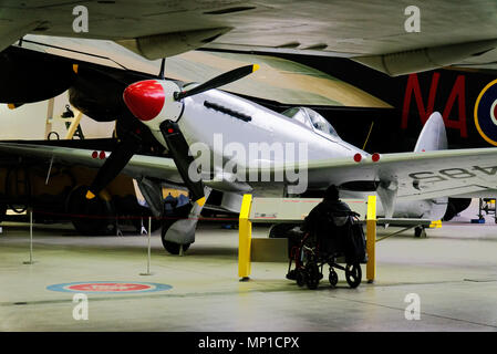 Un homme en fauteuil roulant à la recherche au Spitfire Mk 24 dans le Musée de l'air de Duxford Cambridgeshire, Angleterre, Banque D'Images