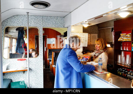 Une femme plus âgée l'achat de thés de la voiture-restaurant sur le pic de fer vapeur Rail, Bakewell, Derbyshire, Angleterre Banque D'Images