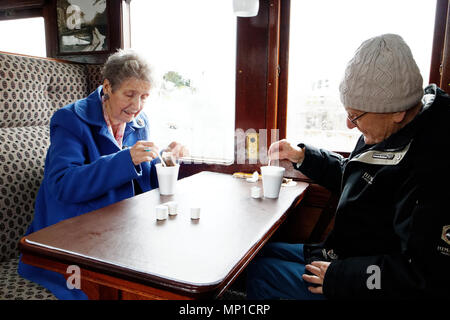 Un homme et une femme âgés faire du thé sur le train à vapeur sur rail pointe un jour pluvieux de Bakewell, Derbyshire Banque D'Images