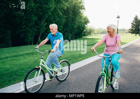 Happy mature couple laughing et obtenir la joie d'activités de plein air. Week-end actif, à la retraite sur les bicyclettes Banque D'Images