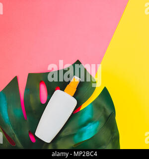 Jungle tropicale Feuilles monstera palmier bouteille vide de l'écran solaire et immersive sur carré lumineux jaune et rose papier duotone arrière-plan. Vacances d'été cre Banque D'Images