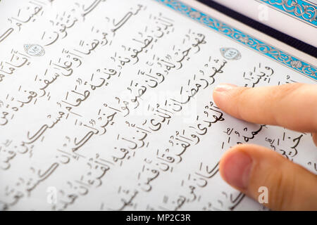 Garçon musulman soulignant le mot : le mois sacré du Ramadan ( ) pendant la lecture du Quraan dans une mosquée Banque D'Images