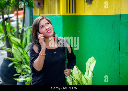 Attractive Asian Woman talking on her smartphone en plein air dans les Philippines. Banque D'Images