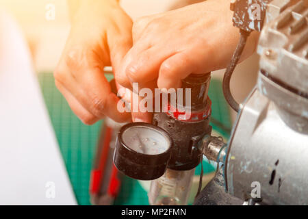 Close-up of a woman working ajuste le capteur sur un aérographe gris métal Banque D'Images