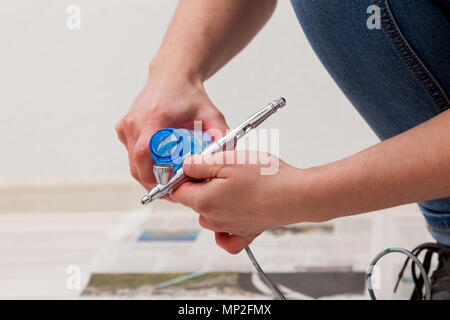 Close-up of a woman artist en jeans nettoie et prépare l'aérographe pour les travaux de peinture des murs. Banque D'Images