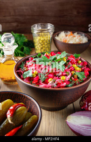 Vinaigrette salade avec des légumes bouillis, concombres, choucroute et pois verts en conserve dans une cuvette d'argile. Snack traditionnel russe. Fo végétarien Banque D'Images