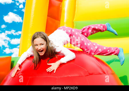 Happy little girl ayant beaucoup de plaisir sur un château gonflable lors d'un saut. Banque D'Images