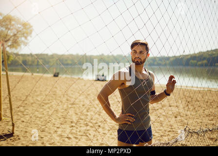 Un sportif barbu est par le filet sur la plage. Banque D'Images