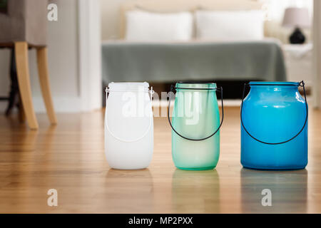 Trois pots de verre avec différentes tailles et couleurs sur un plancher en bois, d'intérieur accueil l'arrière-plan. Banque D'Images